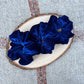 Three blue scrunchies on a wooden slice with a textured background